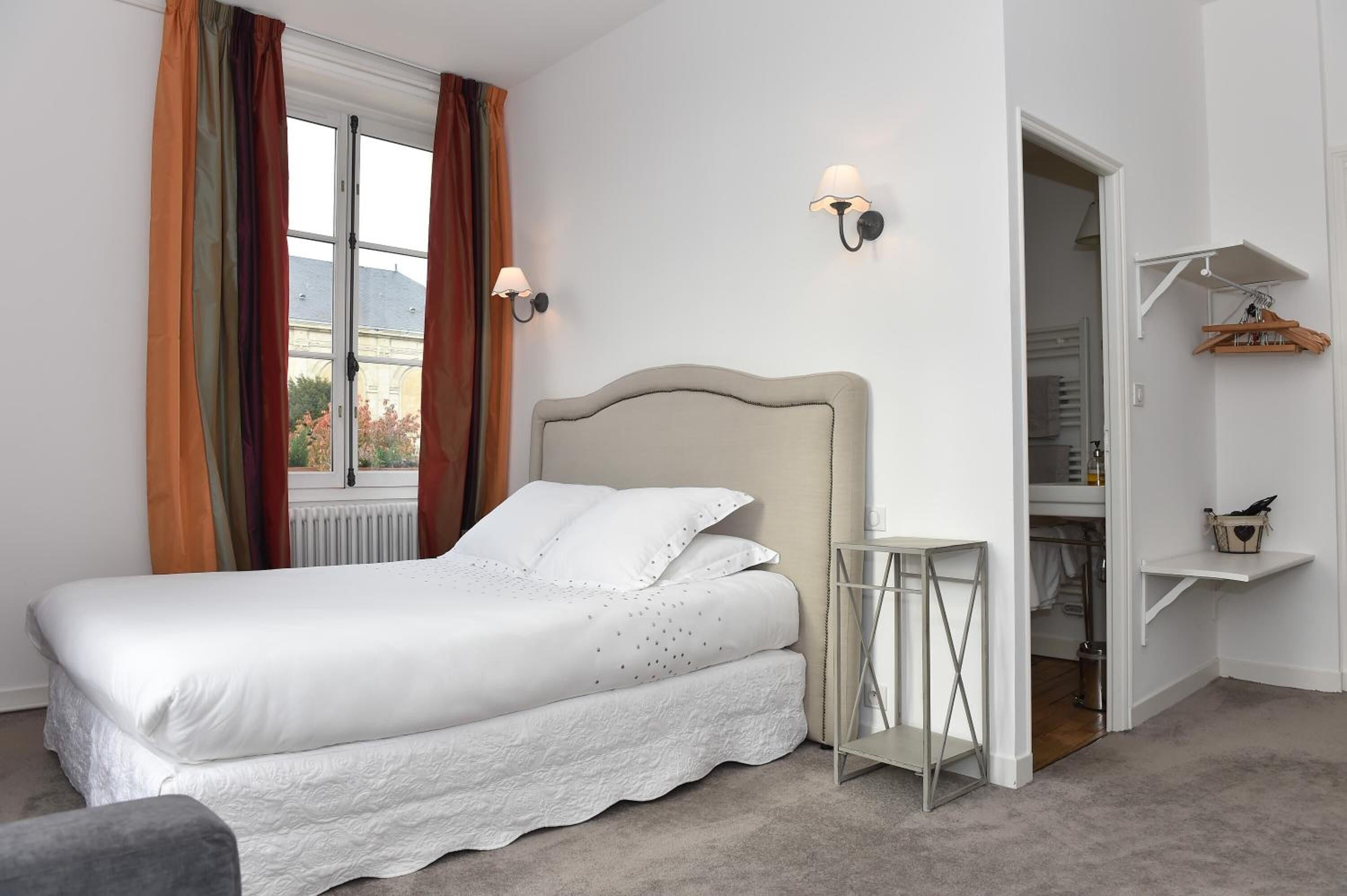 A neatly arranged bedroom with a bed, a small table, and a closet with hanging clothes.