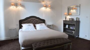 A neatly arranged bedroom with a large bed, bedside lamps, a dresser, and a mirror.