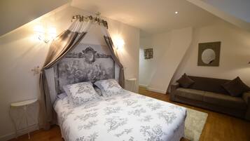 Un dormitorio con cama con dosel, un sofá marrón y una pequeña mesa redonda.