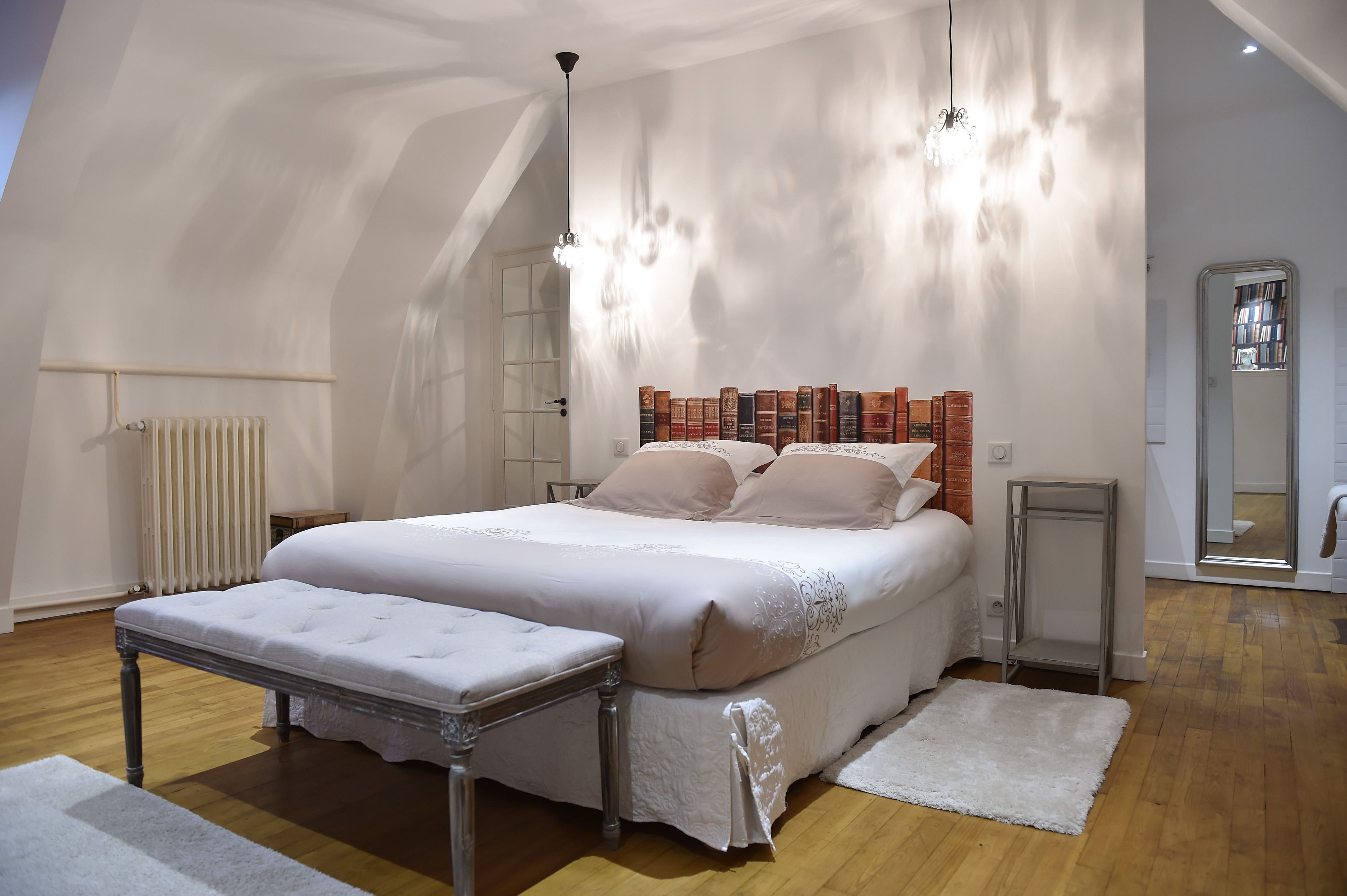 Une chambre à coucher avec un grand lit, une table de chevet, un radiateur et un miroir.