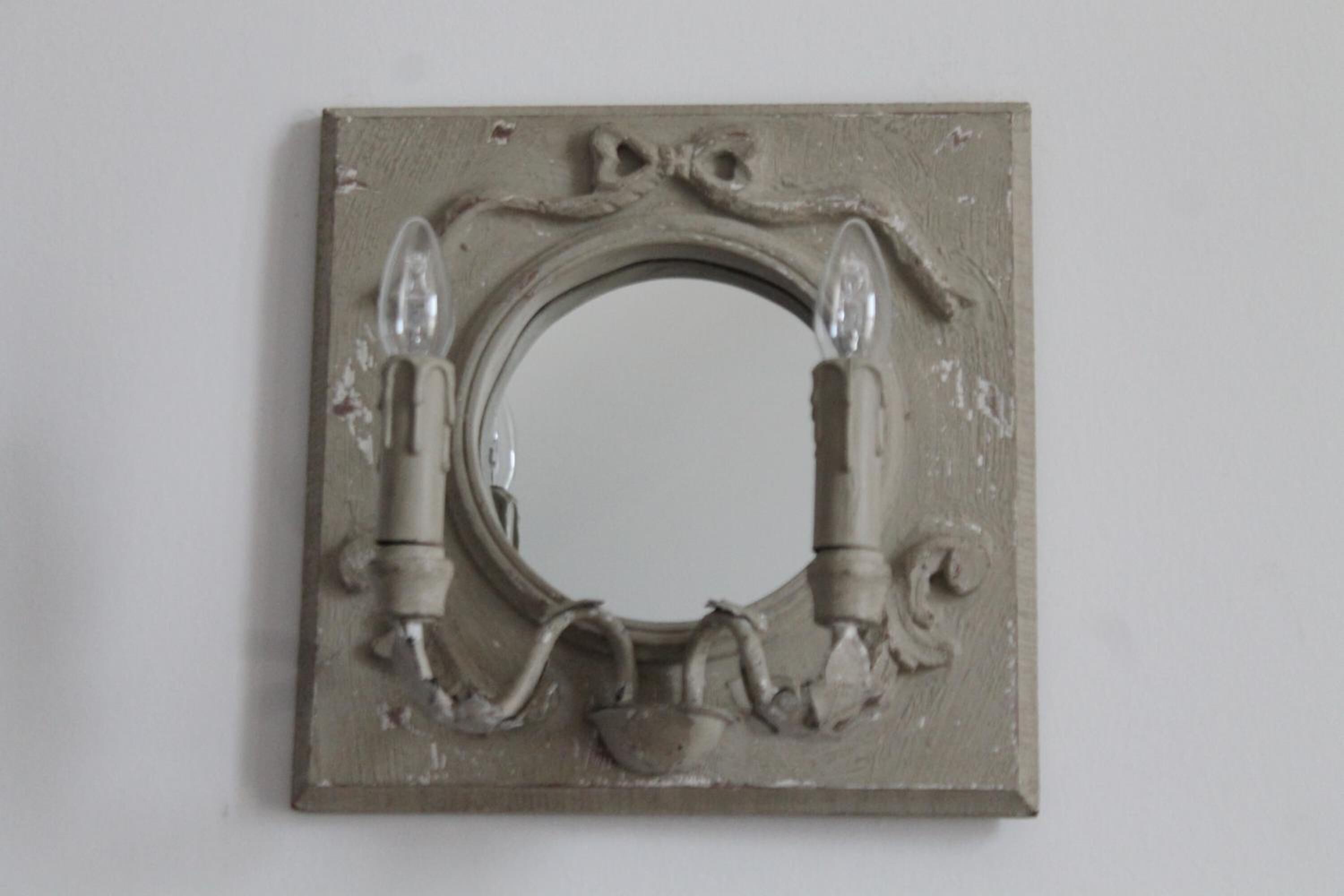 A square metal frame with a circular opening and two cylindrical objects protruding from the sides.