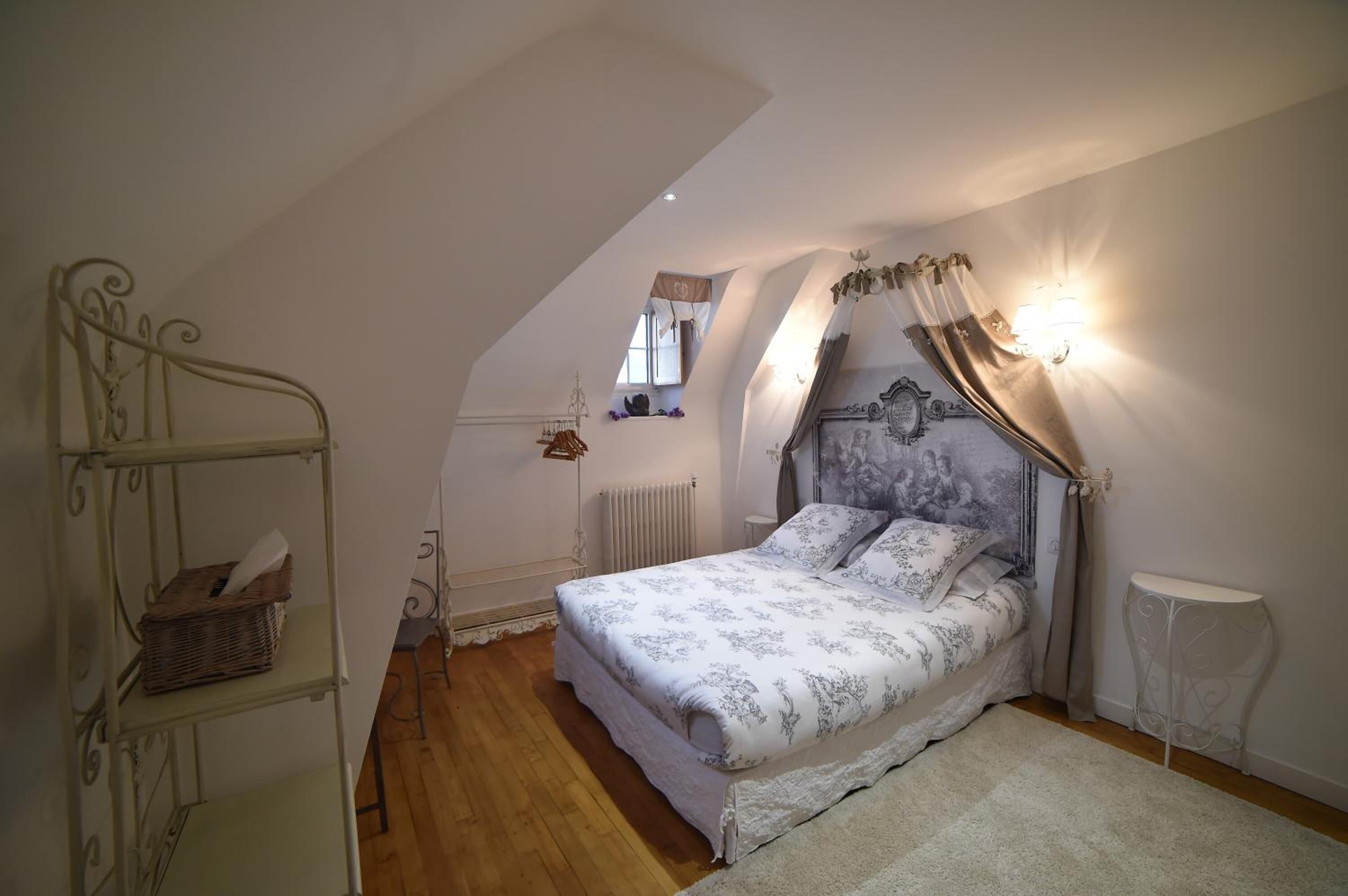 Quarto com cama, radiador, janela, prateleira e mesa de cabeceira.