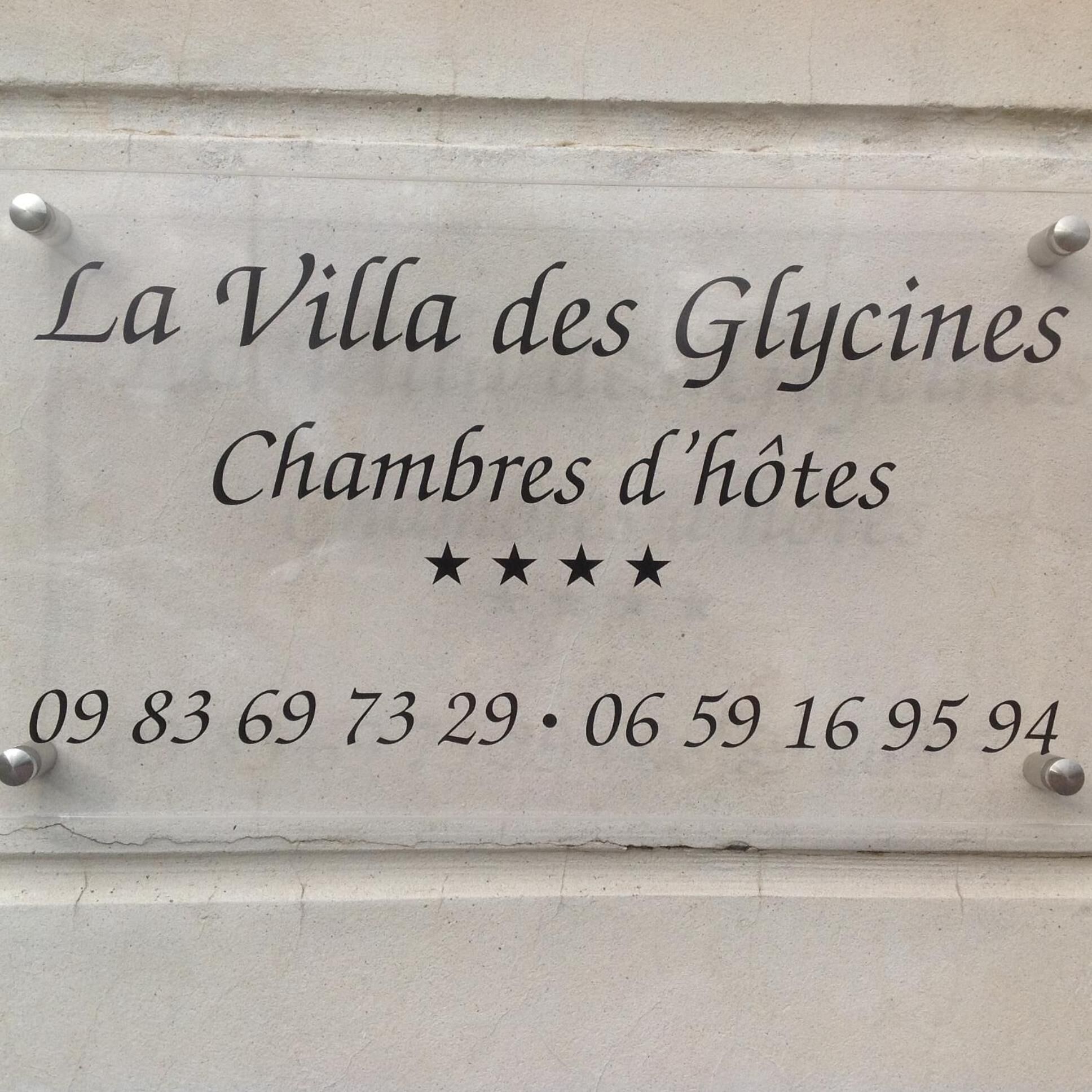 Señal de 'La Villa des Glycines' con la dirección '09 83 69 73 29 · 06 59 16 95 94' y tres estrellas que indican la calificación del hotel.