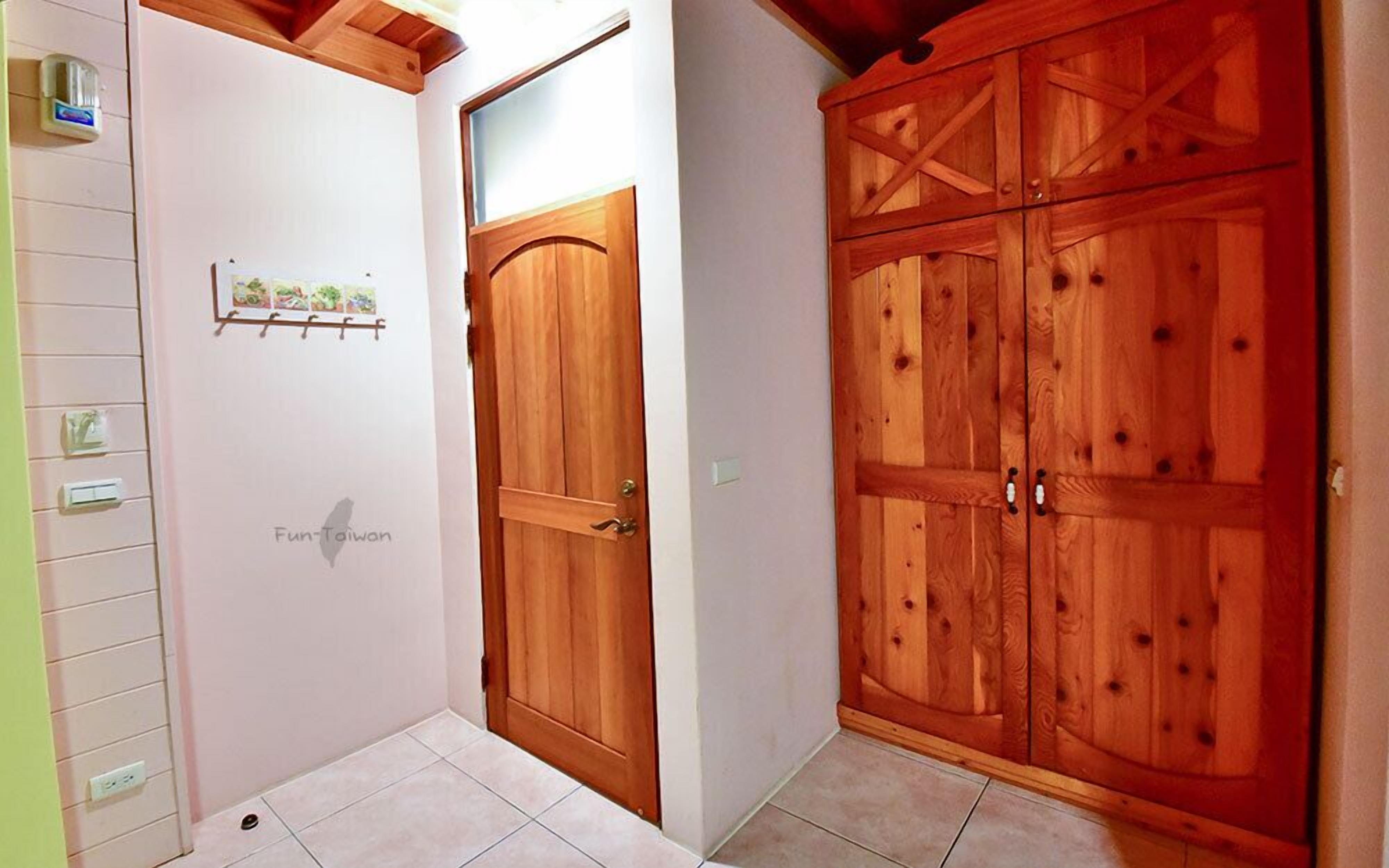 A hallway with a wooden door and a large wardrobe with multiple compartments.