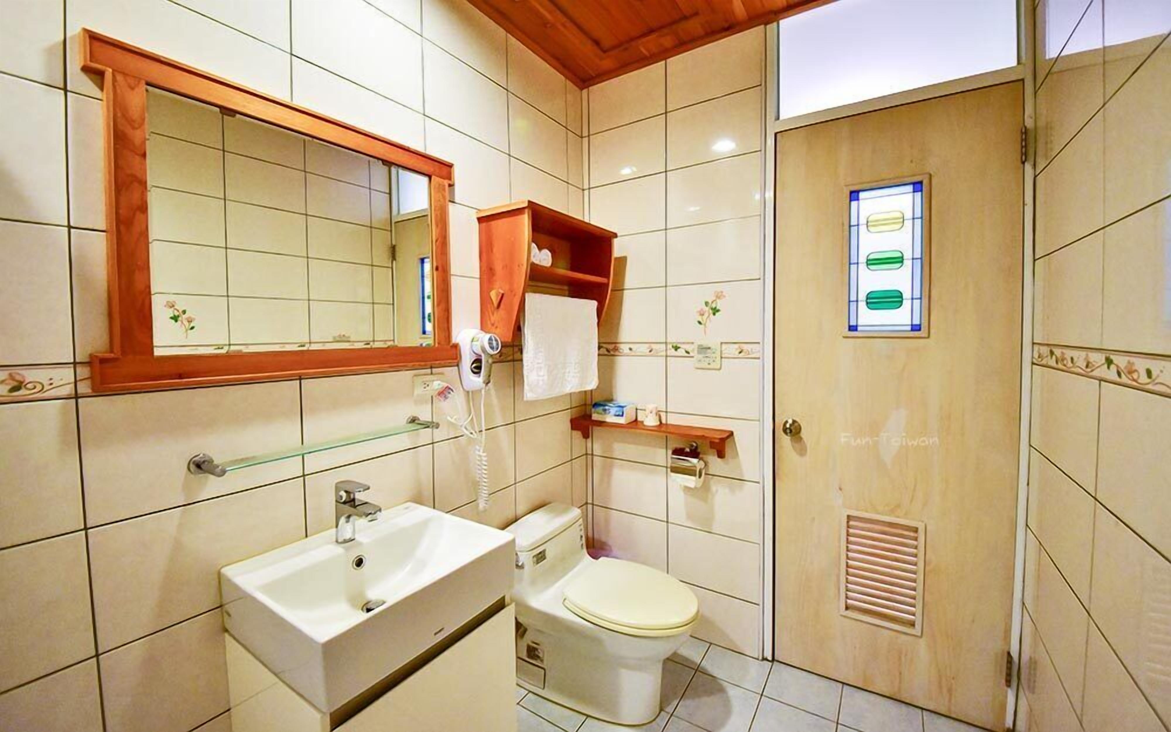 A bathroom with a large mirror, a sink, a toilet, and a shower area.