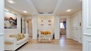A spacious hallway with a white sofa and a glass coffee table, white walls, and a ceiling with recessed lighting. - Rione Trastevere apartment (Rome)