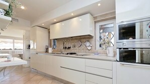 A modern kitchen with white cabinetry, a built-in oven, and a large window. - Rione Trastevere apartment (Rome)
