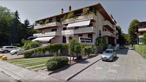 Een meerhoog hotel met balkons, een trap en een parkeerplaats.