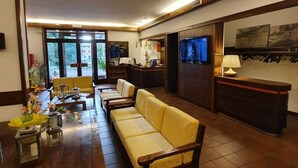 Een ruime woonkamer met een houten salontafel, een gele bank en een aan de muur bevestigde televisie.