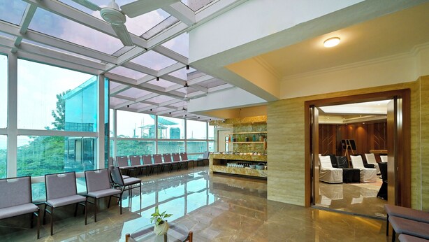 A spacious lobby with a glass ceiling, seating area, and a reception desk. - Maharaja Regency (Satara)