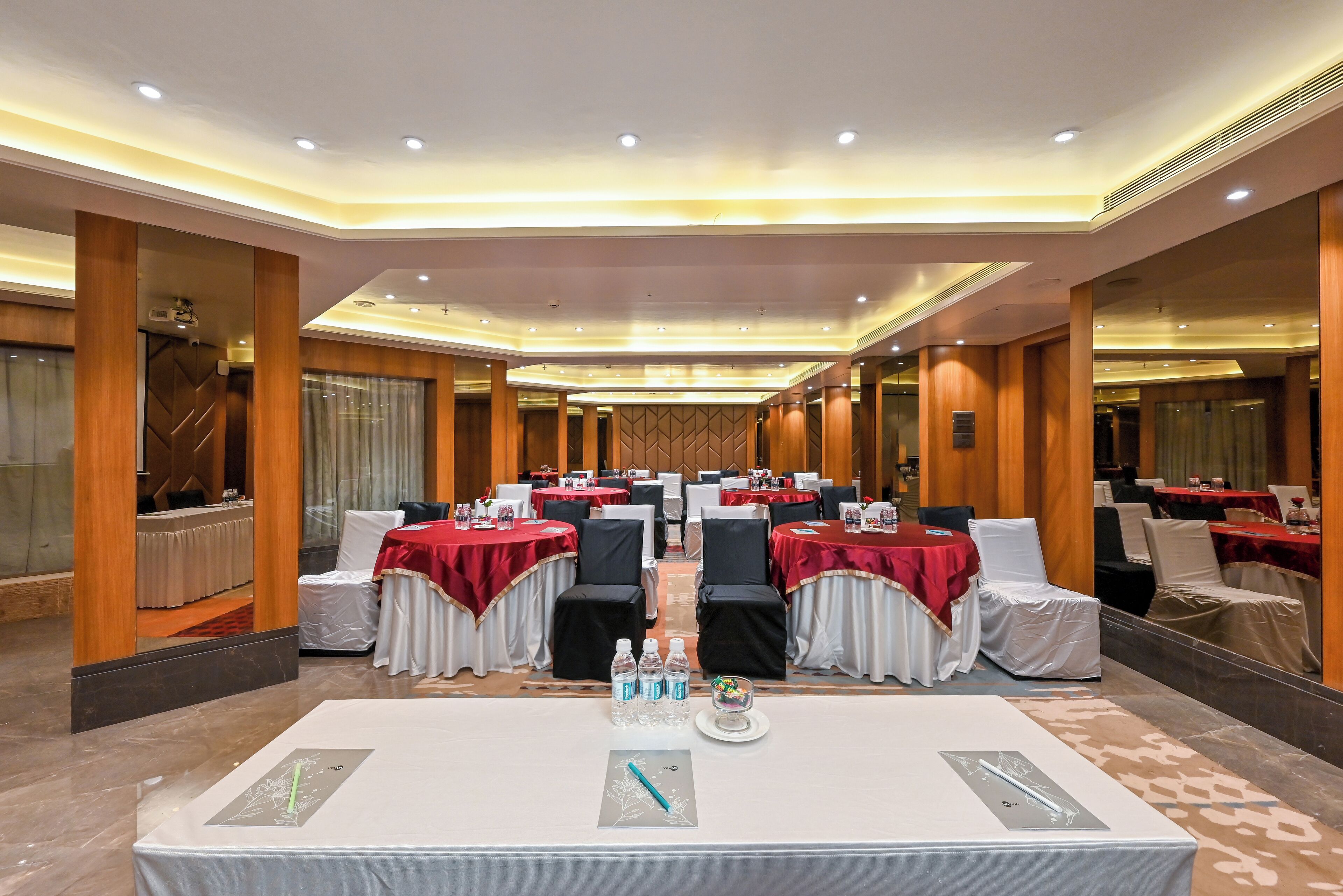 A conference room with tables set for meetings, equipped with water bottles and a digital device on the table.