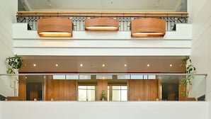 A modern hotel lobby with a glass partition, wooden paneling, and a polished marble floor. - Maharaja Regency (Satara)