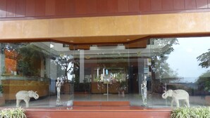 A building entrance with a glass facade, a reception desk, and a staircase leading up to the entrance. - Maharaja Regency (Satara)