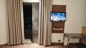 A hotel room with two beds, a TV, a balcony, and a small table. - Maharaja Regency (Satara)