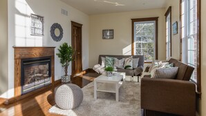 A living room with a fireplace, a sofa, a coffee table, and a large window. - QuickStay Lake Simcoe Homestyle Cottage Private Beach (Georgina)