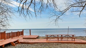 A wooden deck with picnic tables overlooking a calm body of water. - QuickStay Lake Simcoe Homestyle Cottage Private Beach (Georgina)