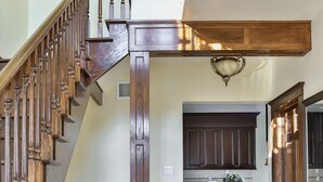 A spacious hallway with a wooden staircase, a kitchen area with dark cabinets, and a tiled floor. - QuickStay Lake Simcoe Homestyle Cottage Private Beach (Georgina)