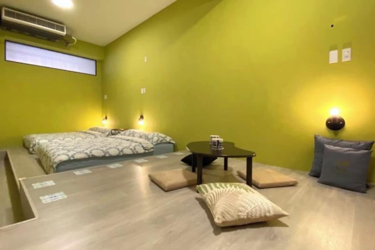 A room with a bed, a small table, and a wall-mounted air conditioner.