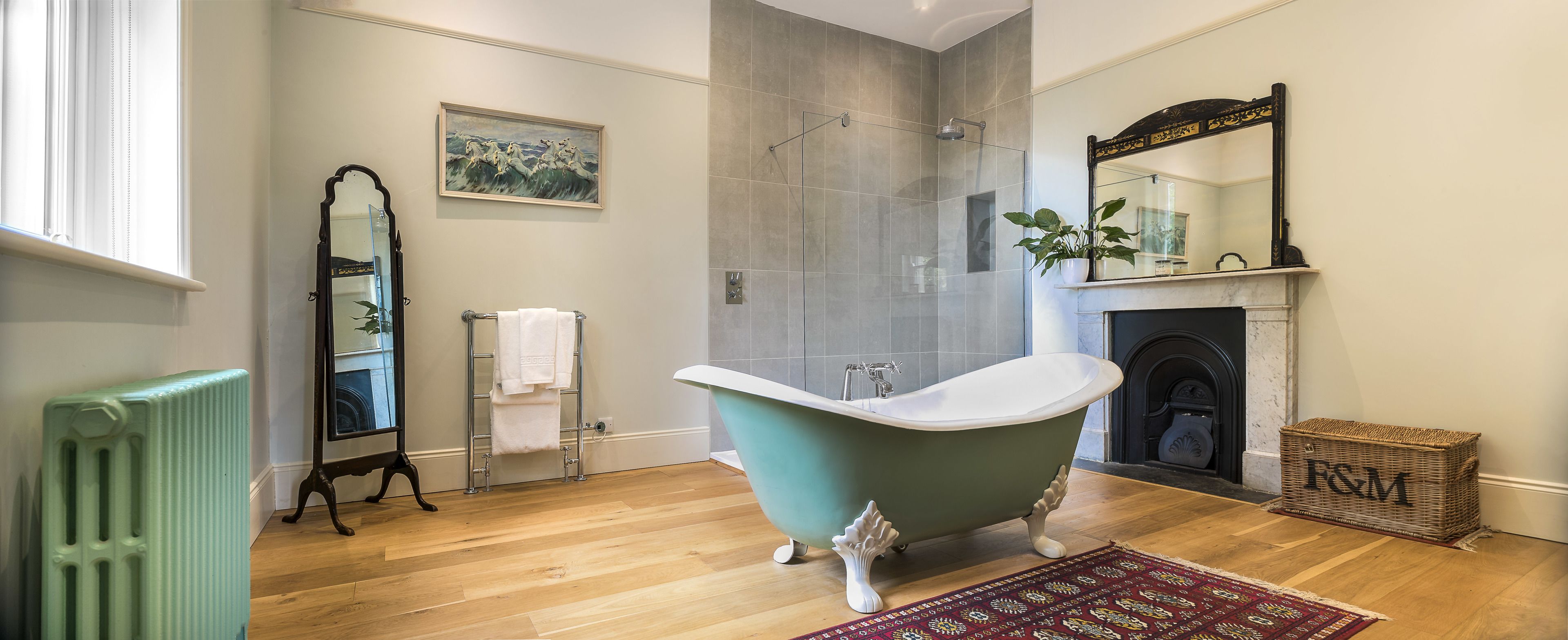 A bathroom with a freestanding bathtub, a shower, a large mirror, and a fireplace.