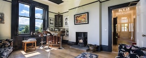 Relax by the fireplace in a cozy seating area with a sofa and bar stools, featuring a large window with an outdoor view.