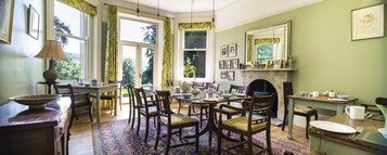 Uma sala de jantar com lareira, mobiliário de madeira e vista para o exterior.