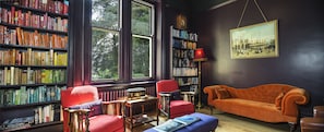 Relax in a cozy reading room with a warm atmosphere, plush seating, and a rich book collection.