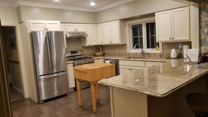 A modern kitchen with stainless steel appliances, white cabinetry, and a granite countertop. - 1860 House Inn and Vacation Rental Home (Stowe)
