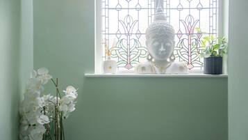 A Buddha statue on a windowsill with a stained glass window behind it.