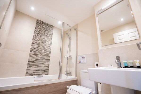 A modern bathroom with a glass-enclosed shower, a white sink with toiletries, and a mirror above the sink. - Marlborough house hotel (Oxford)