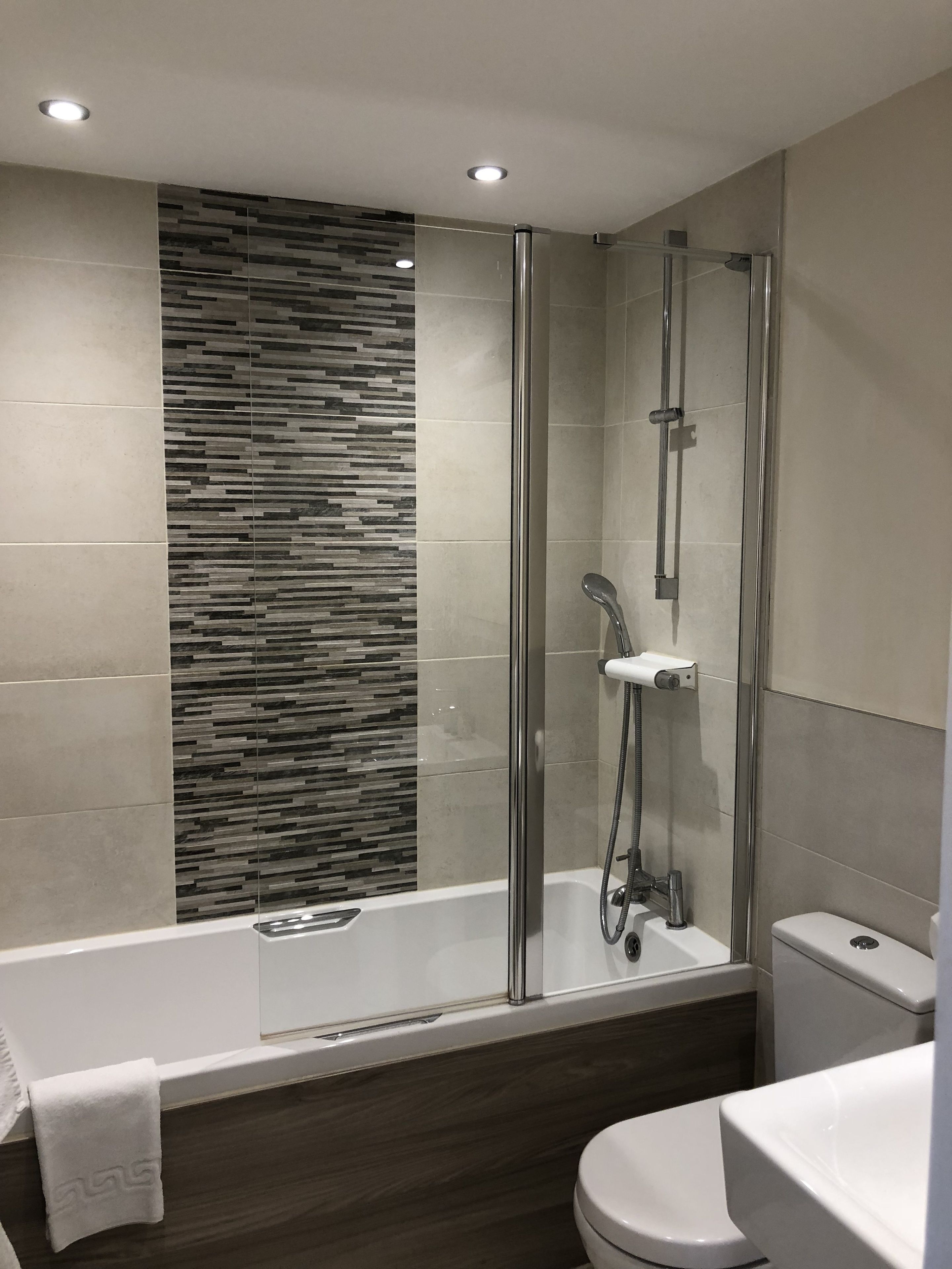 A modern bathroom with a glass-enclosed shower, a bathtub, and a toilet.