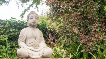 A seated stone statue in a garden setting.