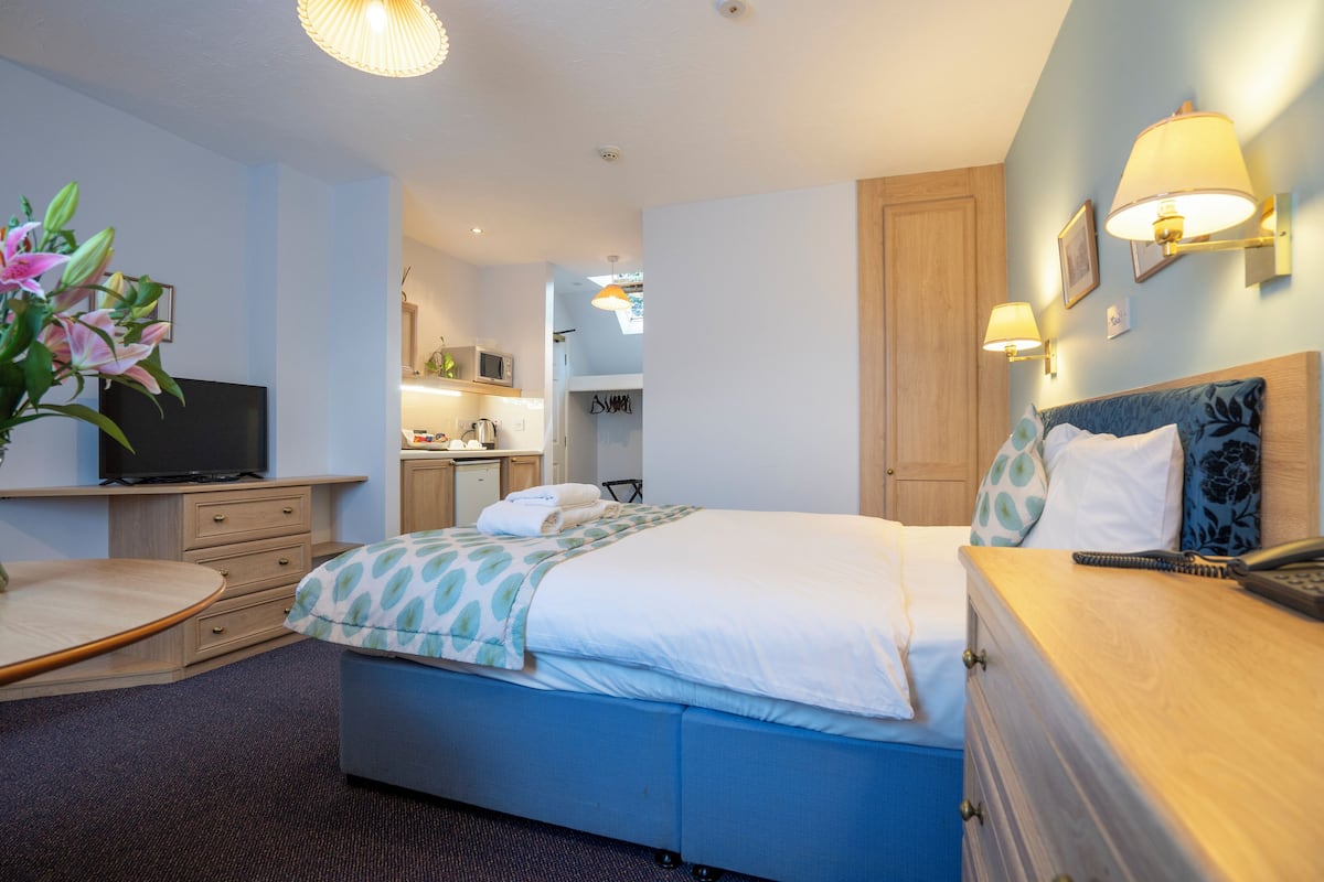 A hotel room with a bed, bedside table, dresser, and a TV.