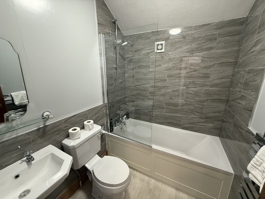 A modern bathroom with a glass-enclosed shower, a white sink, and a toilet.