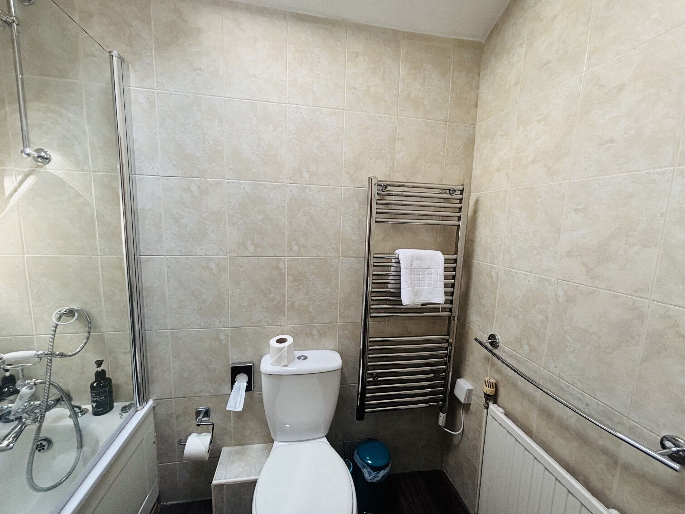 Een badkamer met douche, toilet en handdoekhouder.