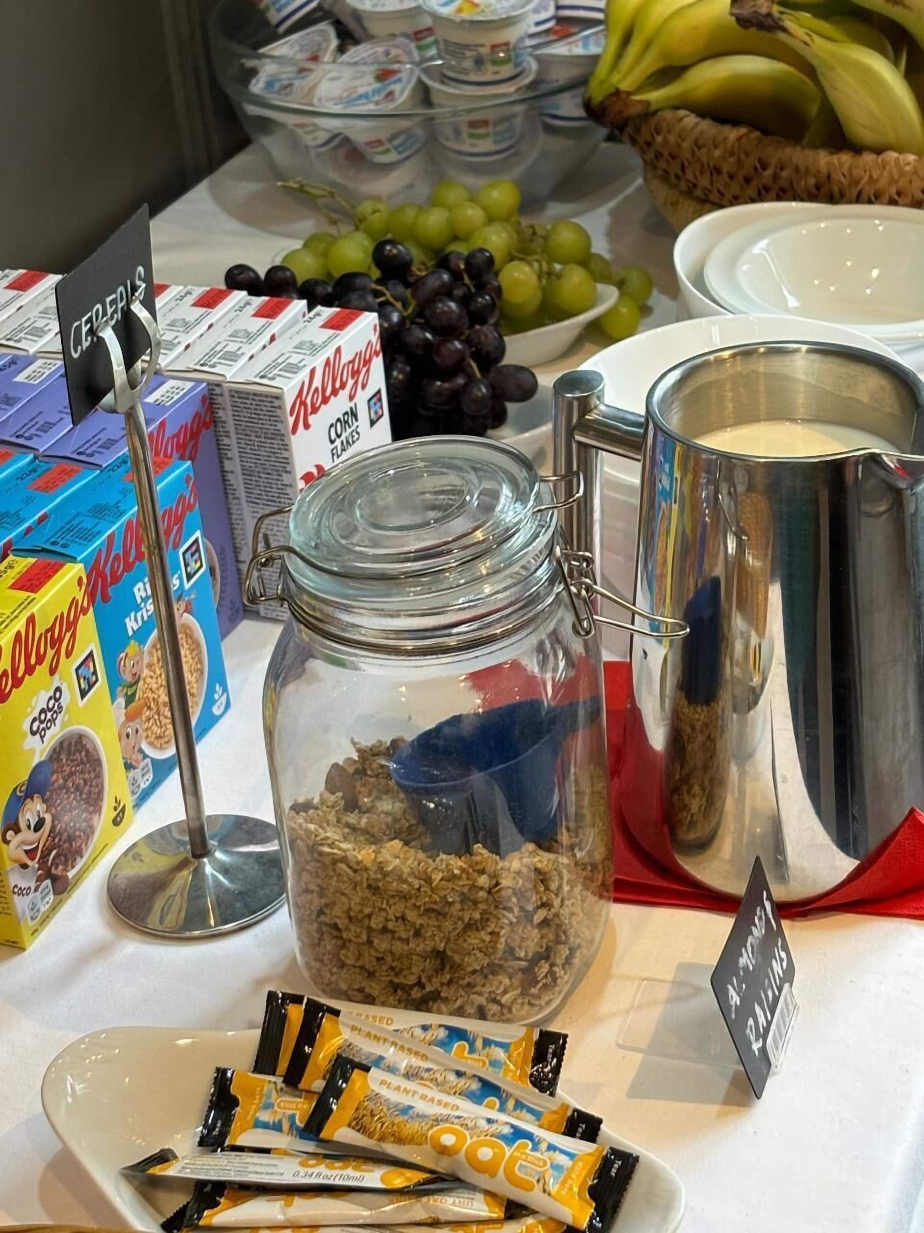 A breakfast buffet with cereal, yogurt, and fruits.