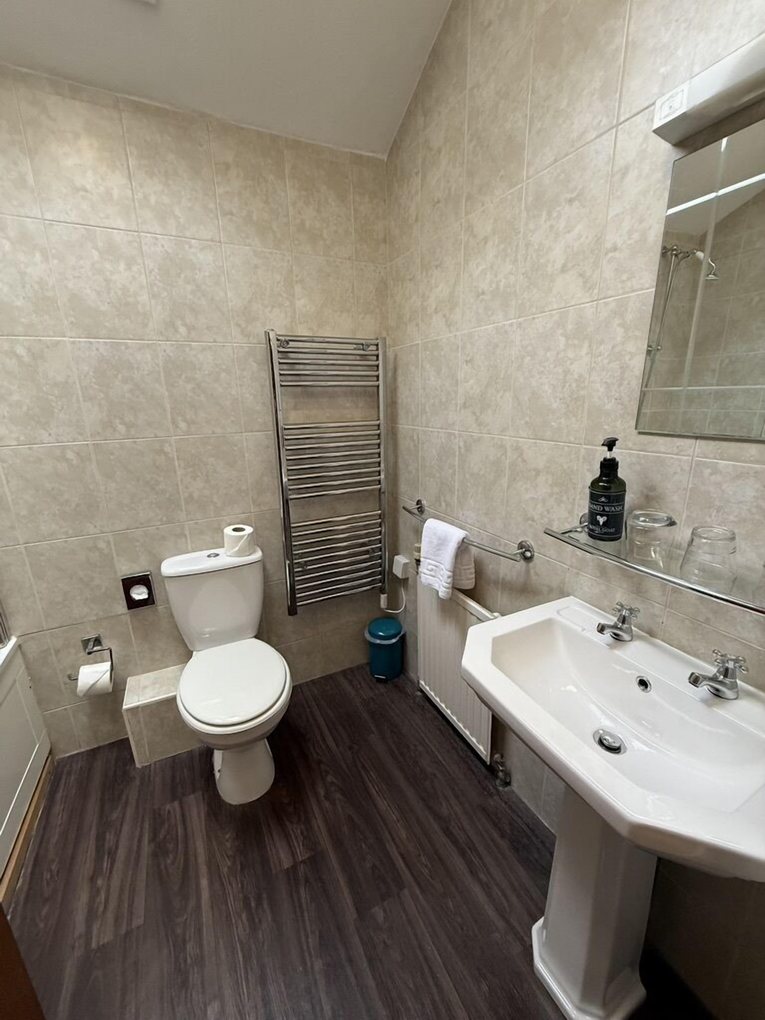 Une salle de bain équipée d’un WC, d’un lavabo, d’un miroir et d’un porte-serviettes.