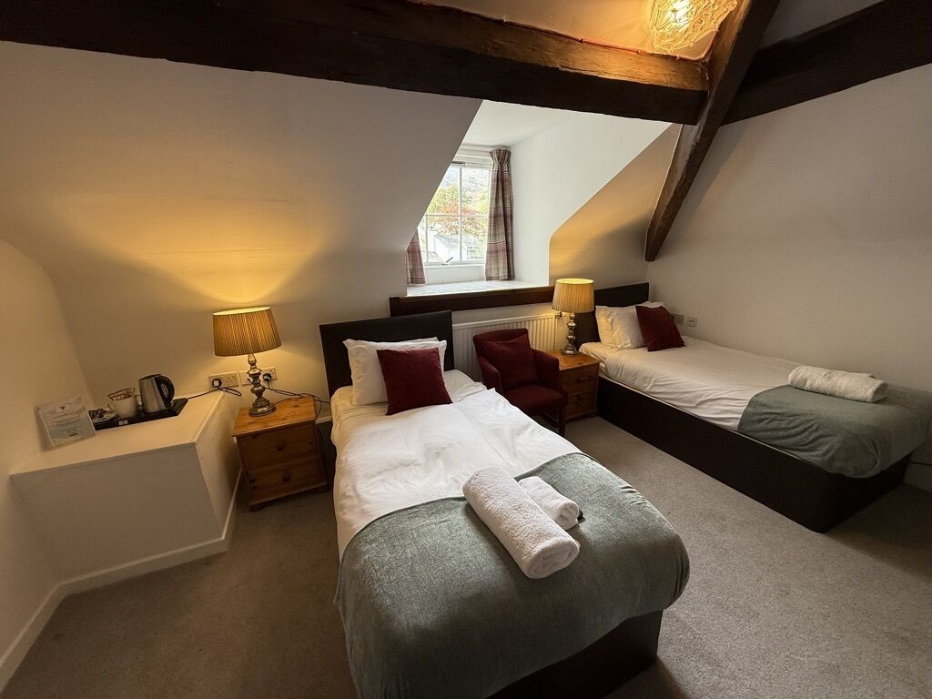 Ein Zimmer mit zwei Betten, einem Fenster und einer Lampe.