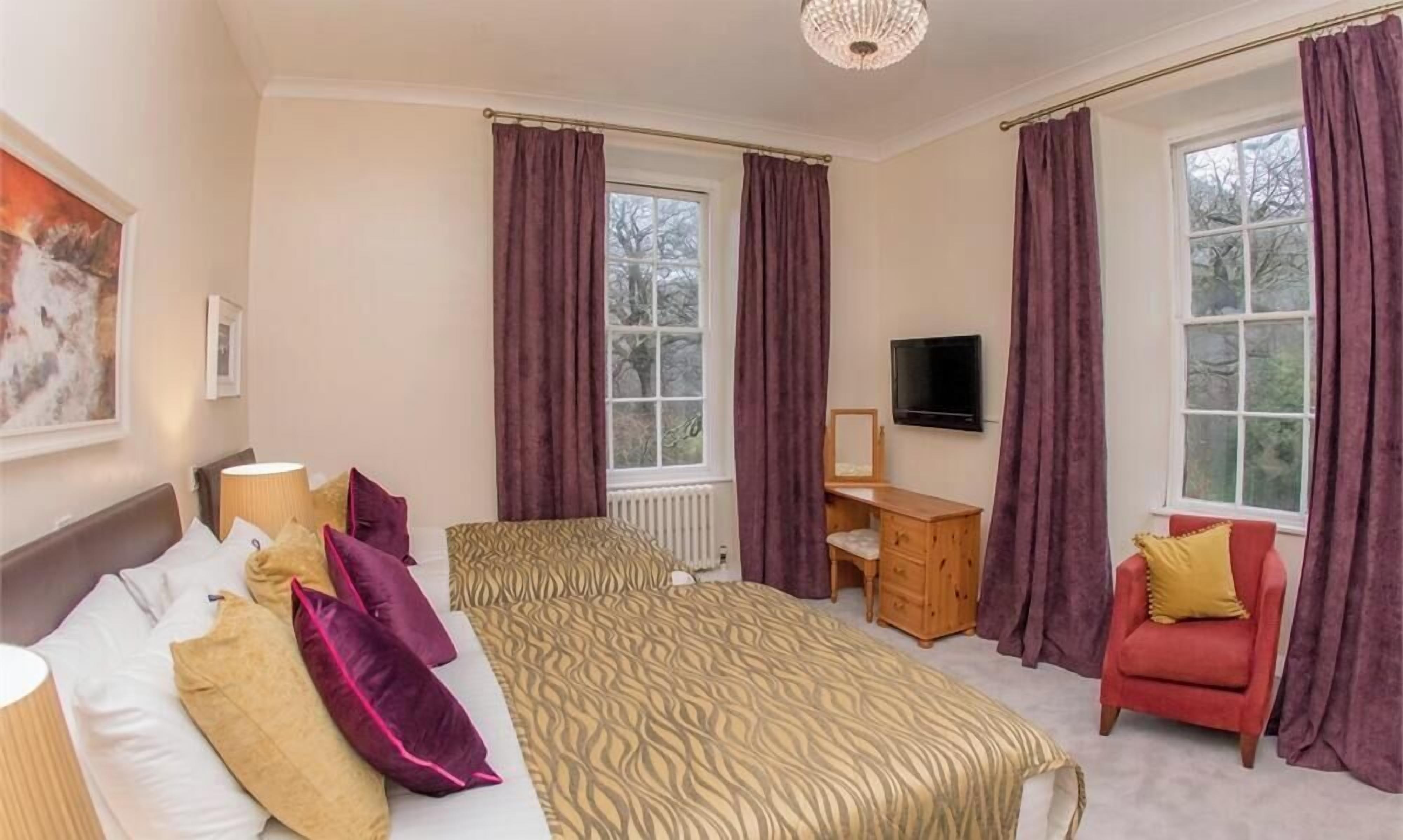 A hotel room with a bed, a desk, a chair, and a TV.