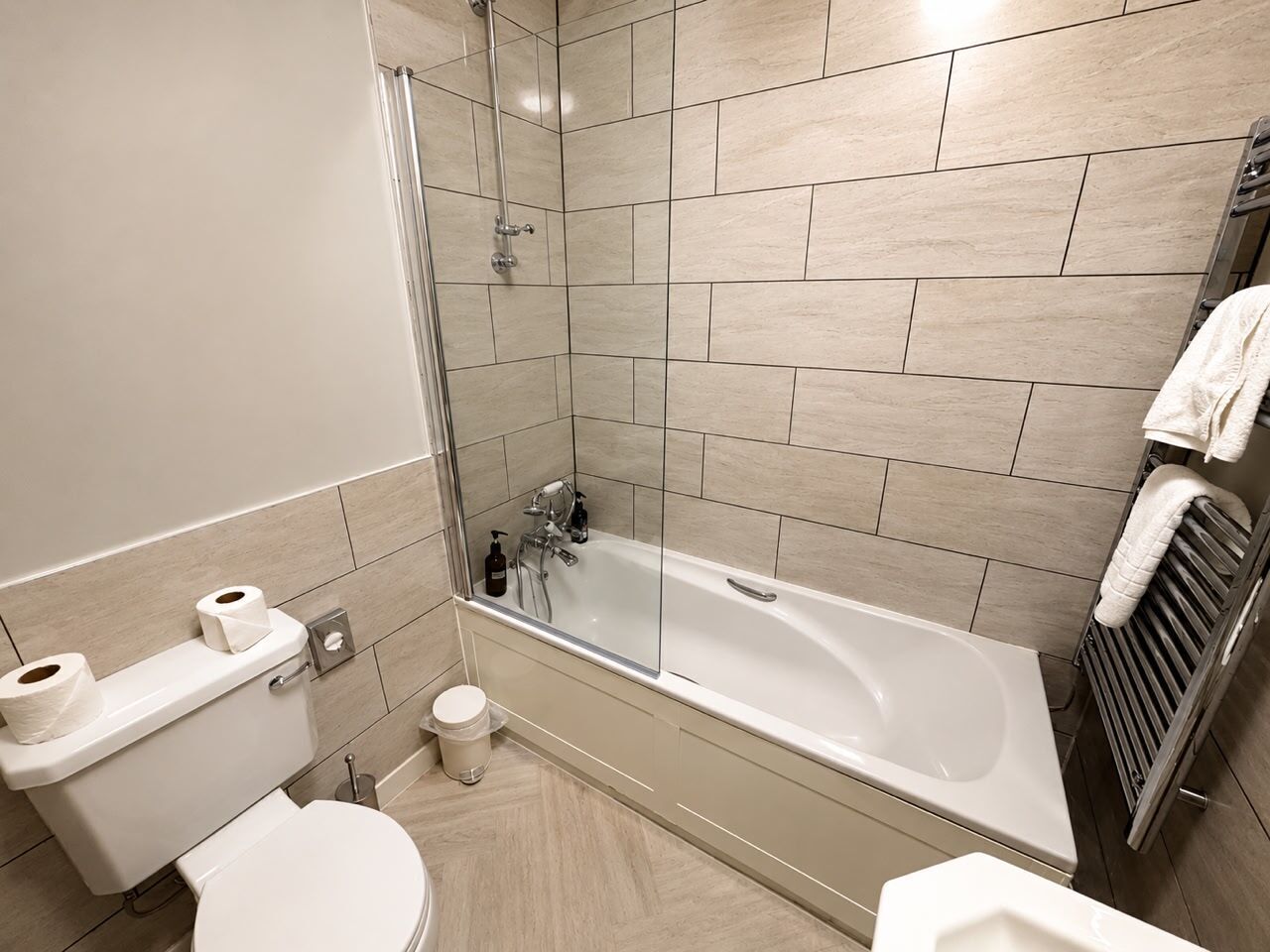 A modern bathroom with a glass-enclosed shower, a toilet, and a bathtub.