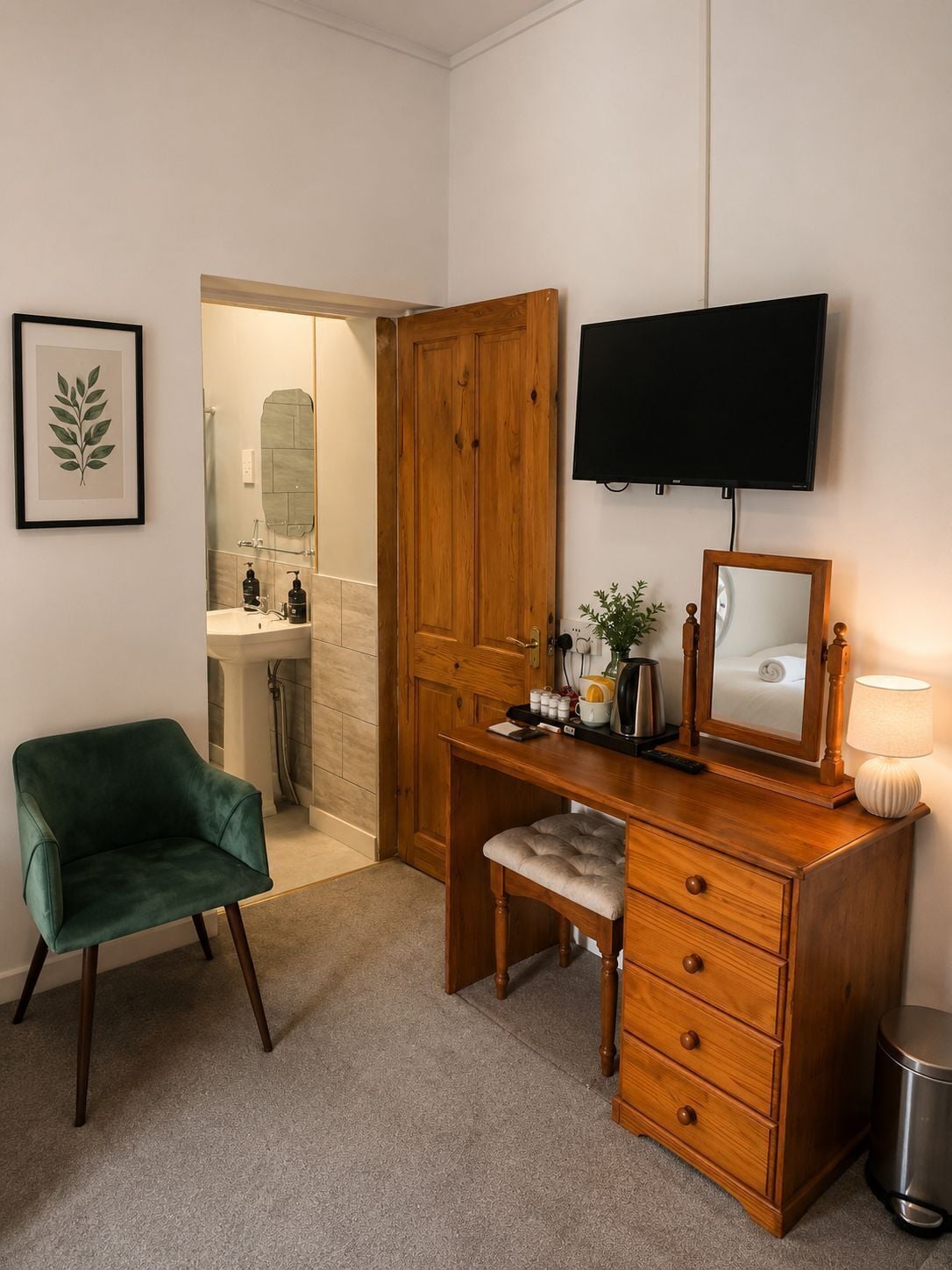 A room with a desk, chair, television, and a mirror.