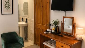 A room with a desk, chair, television, and a mirror.