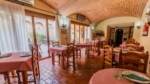 A restaurant with brick flooring, wooden tables and chairs, and a tiled ceiling. - Hotel Rural La Sinforosa (Alange)