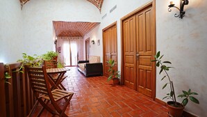 A hallway with a tiled floor, wooden doors, and potted plants. - Hotel Rural La Sinforosa (Alange)