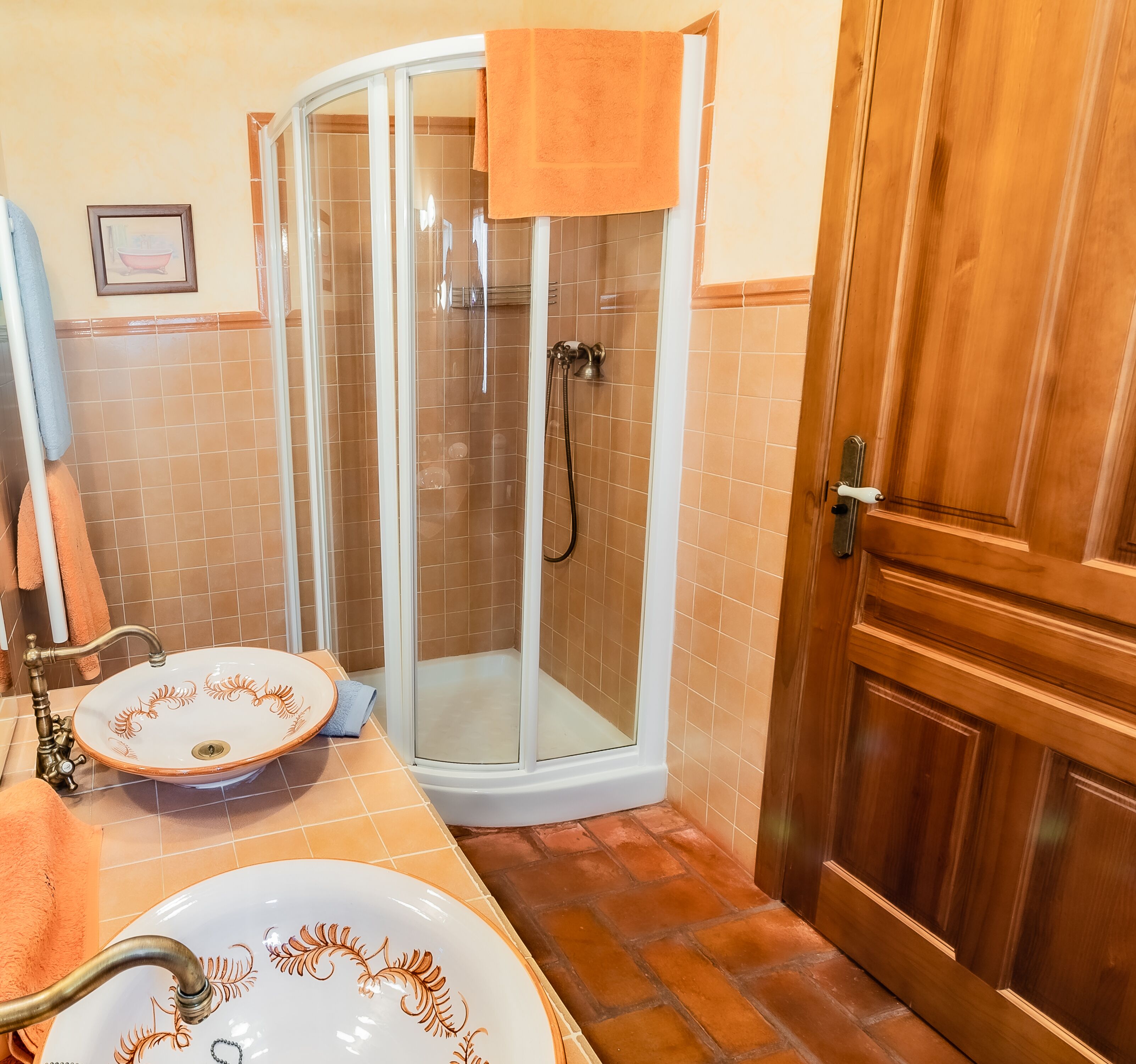 Un baño con cabina de ducha de vidrio, un lavabo con elegantes pomos y una puerta de madera.