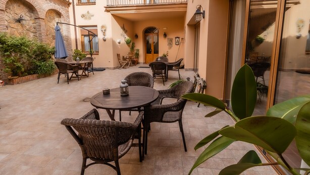 A courtyard with wicker furniture, a wooden door, and potted plants. - Hotel Rural La Sinforosa (Alange)