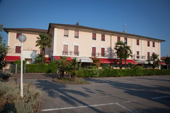 Un bâtiment à deux étages, doté d’un auvent rouge, d’une enseigne indiquant un restaurant, et sous un ciel dégagé.