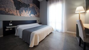 Una habitación de hotel moderna con una cama grande, un escritorio y un mural en la pared.