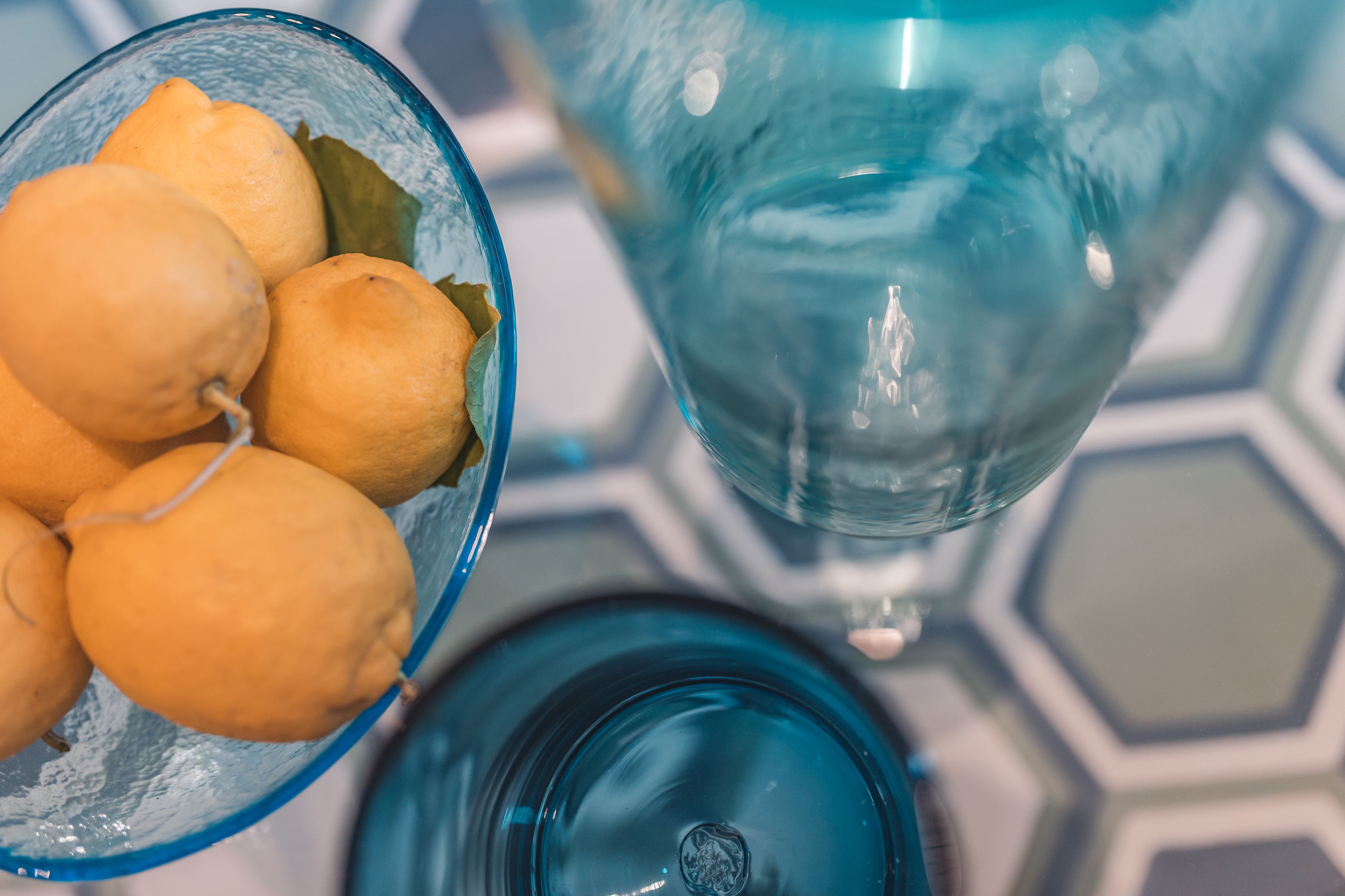 Un saladier en verre contenant des citrons et un objet en verre bleu.