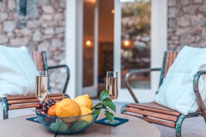 Une table avec un panier de fruits, deux coupes de champagne et une plante en pot.