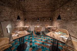 A dining area with hexagonal patterned flooring, wicker chairs, and tables set for dining.